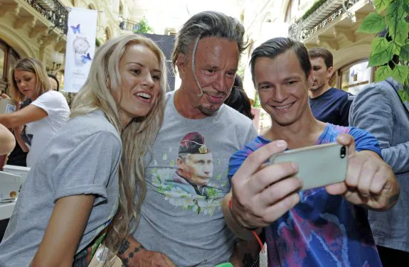 Mickey Rourke, en el centro, se fotografía con dos seguidores y la camiseta de Putin. :: efe