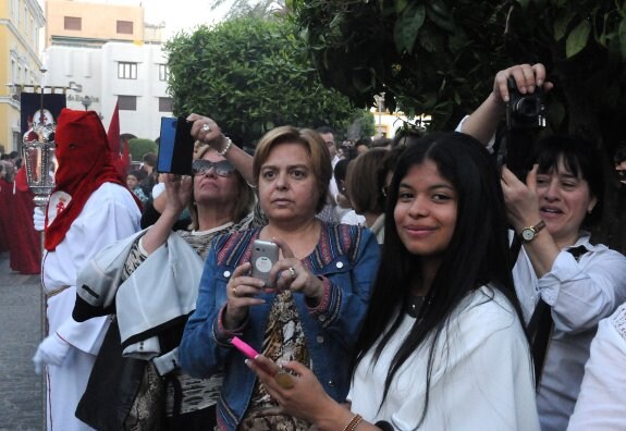 Un grupo de mujeres intentan hacer fotos de la procesión con sus móviles.