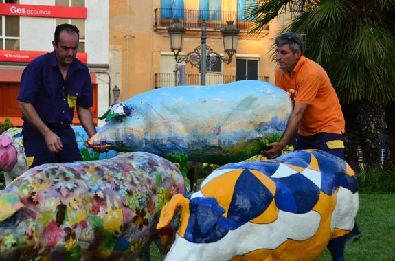 Dos operarios instalando anoche la Iberian Pork Parade en la plaza de San Atón de Badajoz. 