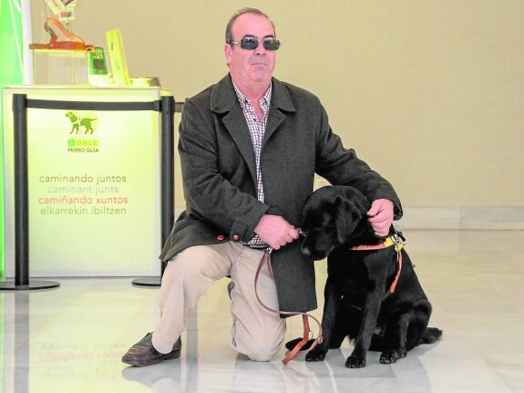 Carlos Mata posa junto a Kayak, su perro guía, en la exposición '25 años caminando juntos'. :: c. moreno