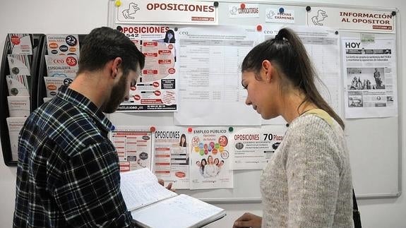 Opositores en una academia consultan la oferta de oposiciones de la Junta