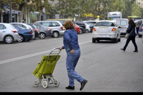 Una señora cruza la calle con su carrito de la compra. :: HOY