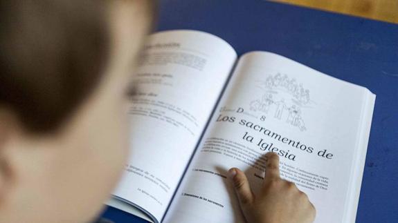 Un estudiante leyendo libro de Religión.