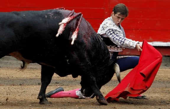 Pase de pecho de 'El Juli' con una rodilla clavada sobre la arena de la plaza de Manizales. :: efe