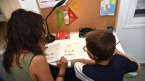 Una mujer ayuda a un niño con sus deberes escolares.