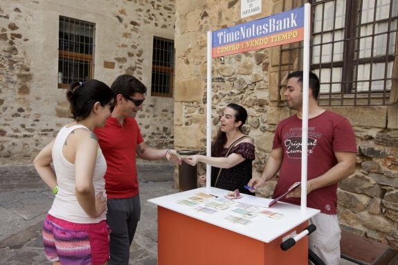 Dos empleados del banco del tiempo atienden a dos visitantes, que efectúan un intercambio. :: l. cordero