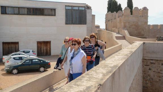 Un grupo de turistas pasea por la Alcazaba con la Facultad de Comunicación al fondo.