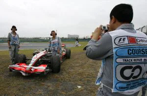EL TROFEO. Trabajadores del Circuito de Shanghai se fotografían junto al coche de Lewis Hamilton. / REUTERS