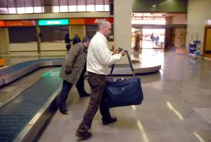 Dos viajeros recogen su equipaje en el Aeropuerto de Badajoz tras llegar el vuelo proveniente de Madrid. / CASIMIRO MORENO