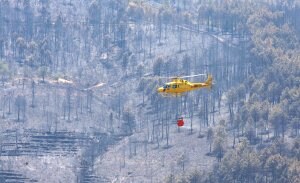 Un helicóptero sobrevuela el ára afectada, cerca de Rubiaco, una de las alquerías de Nuñomoral que fue desalojada. / ANDY SOLÉ