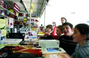 Varios escolares visitando un expositor de libros durante la pasada edición. ::                             HOY