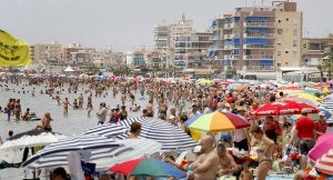 Los bañistas acuden a la playa Lisa de Santa Pola, con una hilera de edificios al fondo. :: EFE