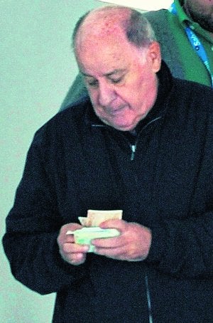 Amancio Ortega cuenta el dinero  de un fajo de billetes. ::
E.P.