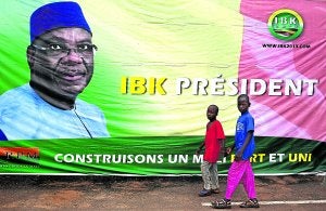 Unos jóvenes pasean frente a un cartel del presidente electo, Ibrahim Bubakar Keita. ::
JOE PENNEY/ REUTERS