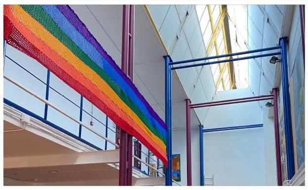 Una gran bandera arcoíris hecha de ganchillo luce en el hall del centro 