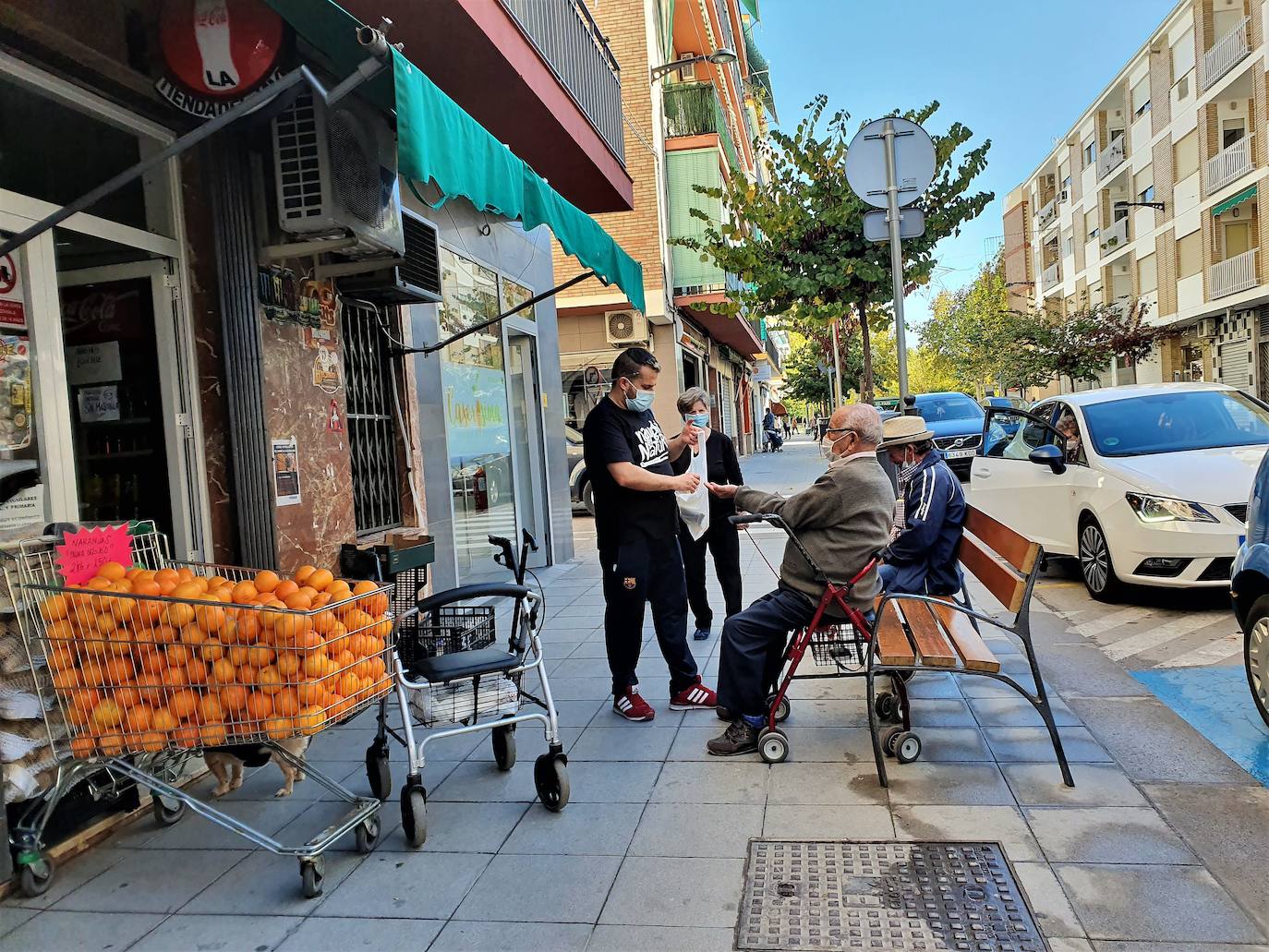 Un propietario de una tienda de la calle Emperador Trajano saca las compras a la calle para un mayor. 