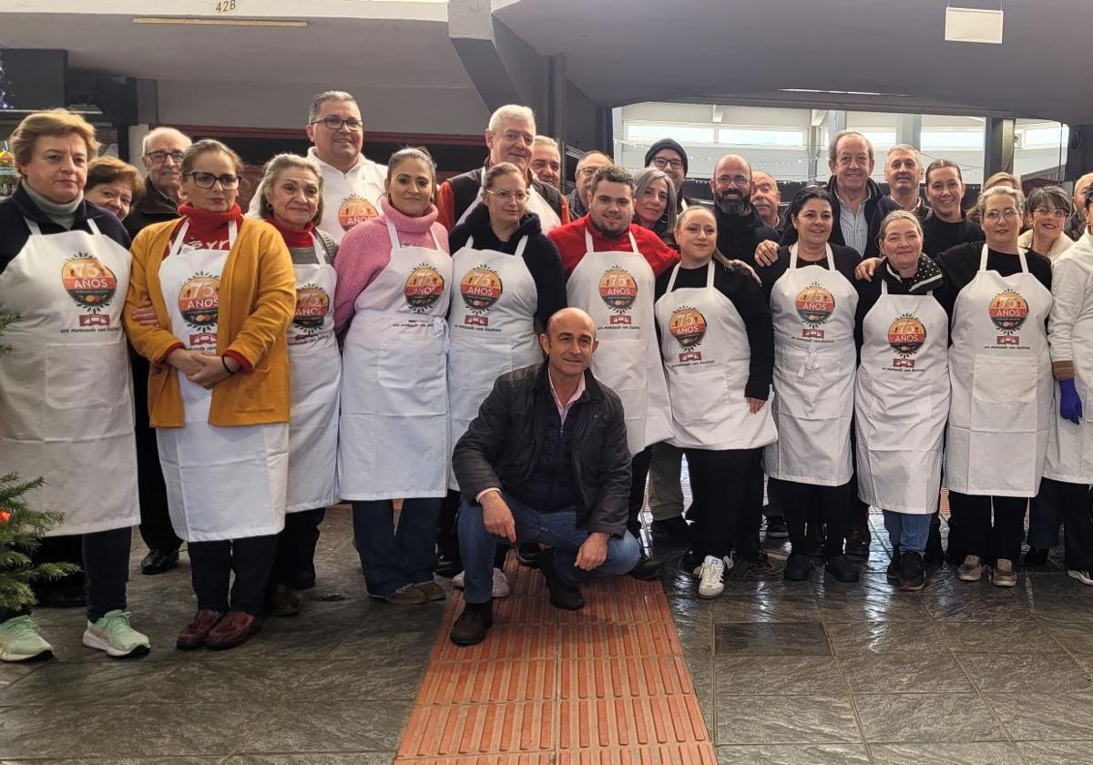 Los comerciantes posan con el mandil conmemorativo del 75 aniversario junto con los autoridades municipales y el encargado.