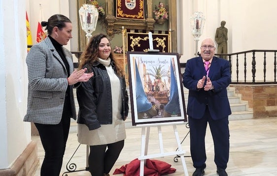 María José Fuentes, Noelia del Moral y Alfonso Soto posan con el cartel ganador del certamen.