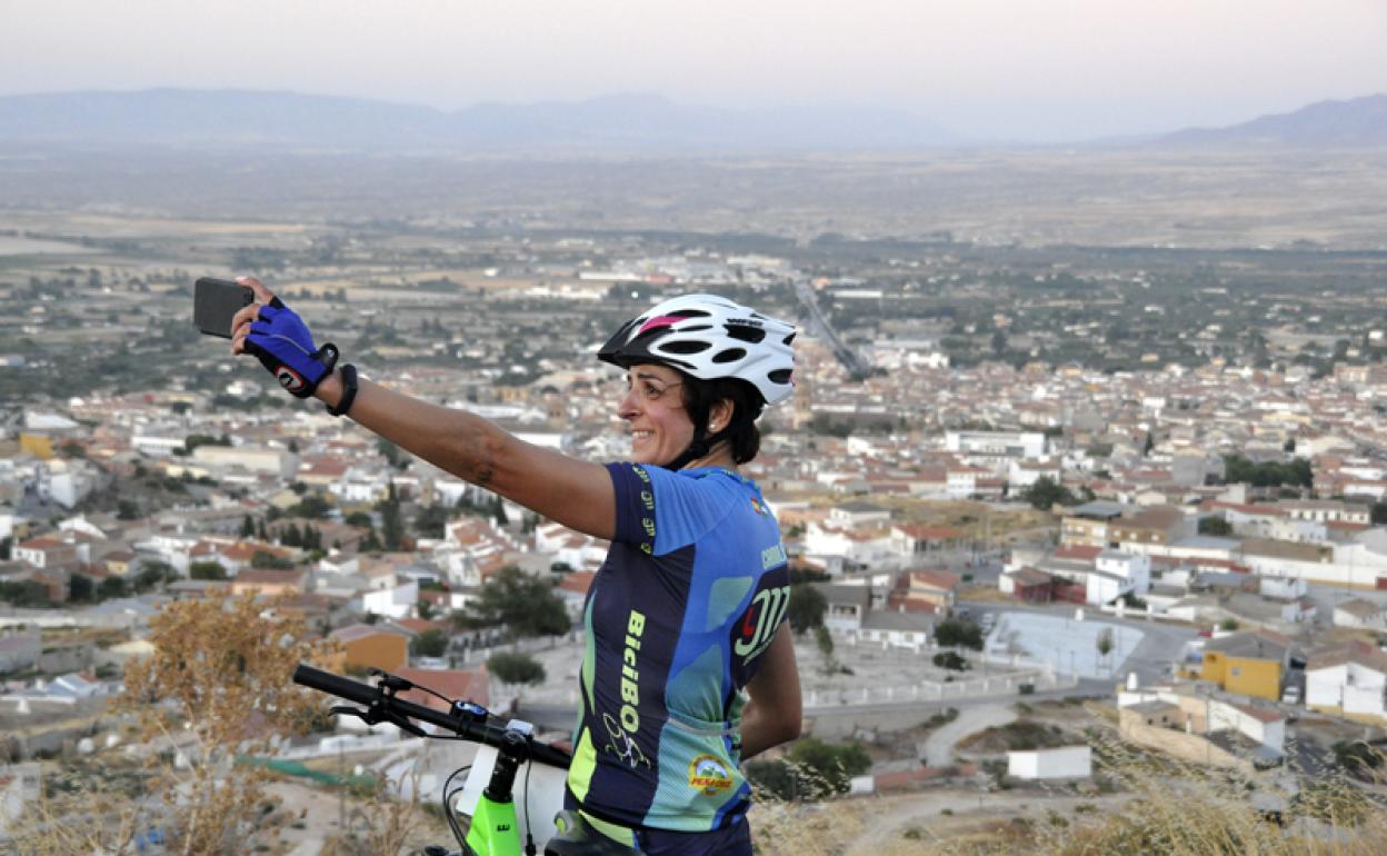 Una deportista satisfecha por cumplir el desafío, haciendose una foto con Baza al fondo 