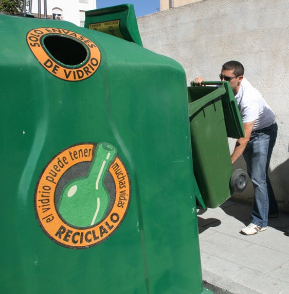 Depositando botellas de vidrio en un contenedor verde