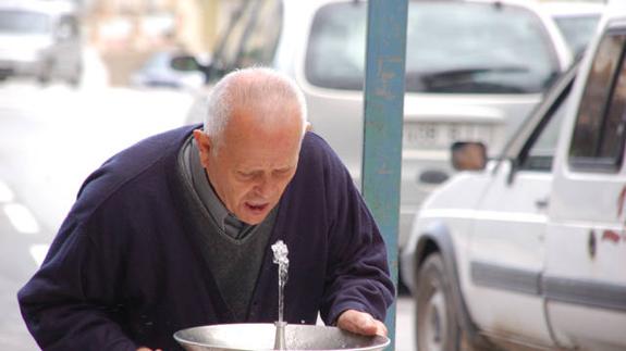 Un hombre mayor bebe agua en una calle de Baza