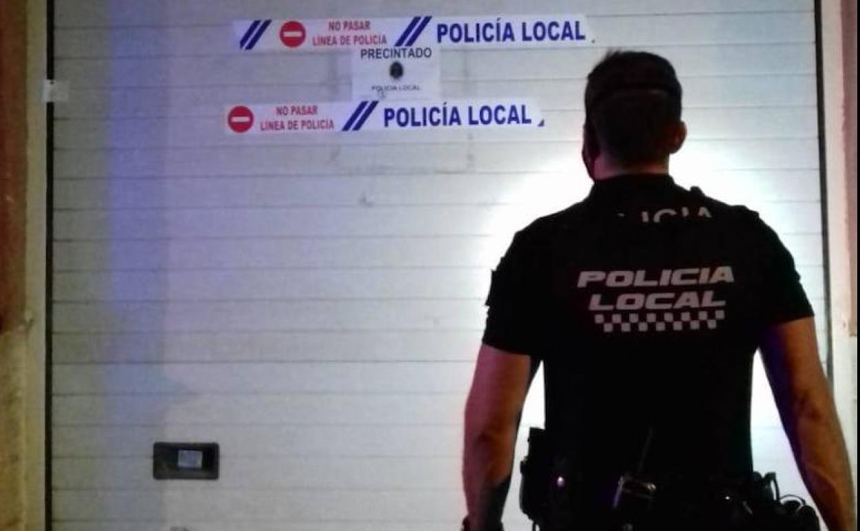 Un agente de Policía Local ante uno de los locales precintados.