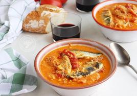 Presentación del plato de sopa de tomates y pimientos servida con lomos de sardina