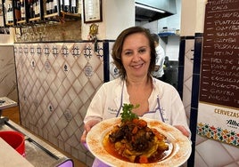 María José Rodríguez tras la barra del Bar Provincias con un plato de rabo de toro.