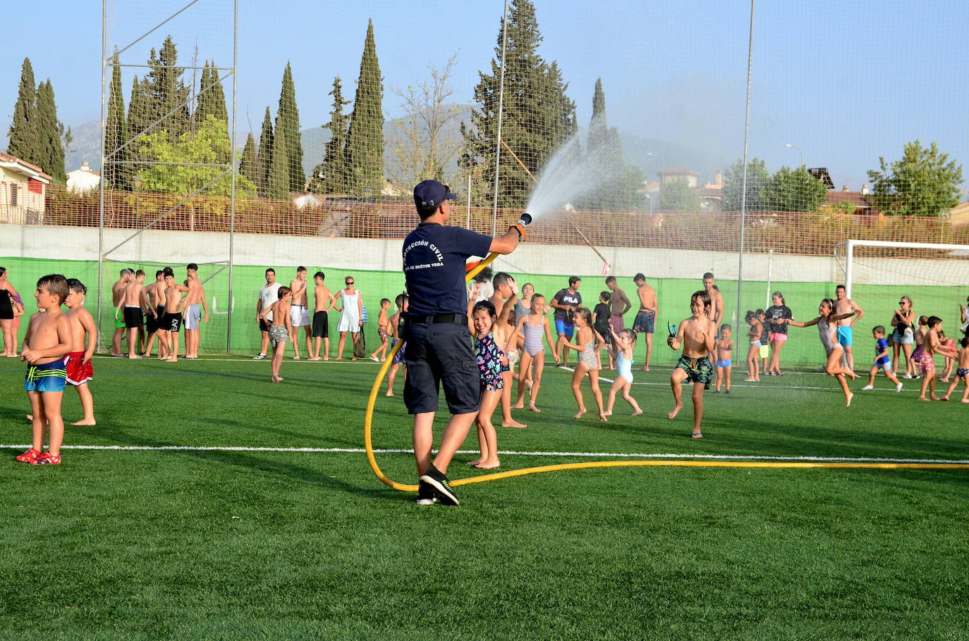 Un voluntario de Protección Civil de Huétor Vega da juego refrescando con una manguera.