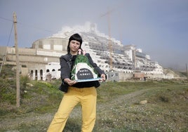 La voluntaria de Greenpeace muestra la tarta-réplica frente al hotel del Algarrobico.