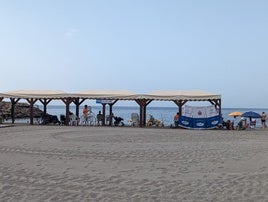 Una playa de Aguadulce con voluntarios de Protección Civil de Roquetas de Mar al lado de sombrillas.