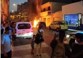 Vecinos observan y graban el vehículo incendiado en el Parador de las Hortichuelas.