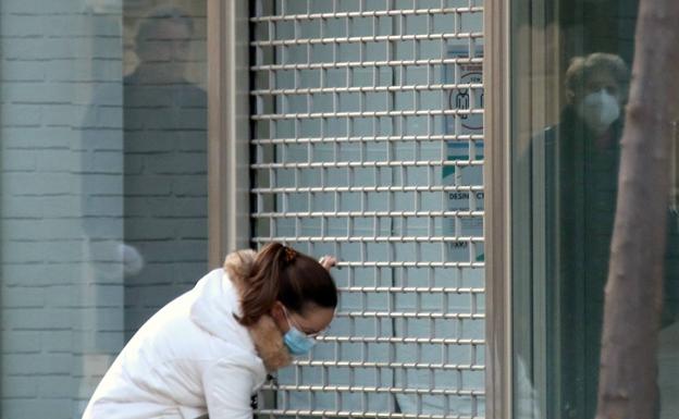Imagen principal - Bajando la persiana de un establecimiento, Rosa intentando mantener el negocio con pedidos de dulces y vista de la calle Mesones donde se encuentra Bolsos Pruden.