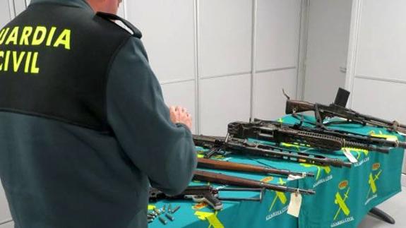 Un Guardia Civil observa algunas de las armas incautadas.