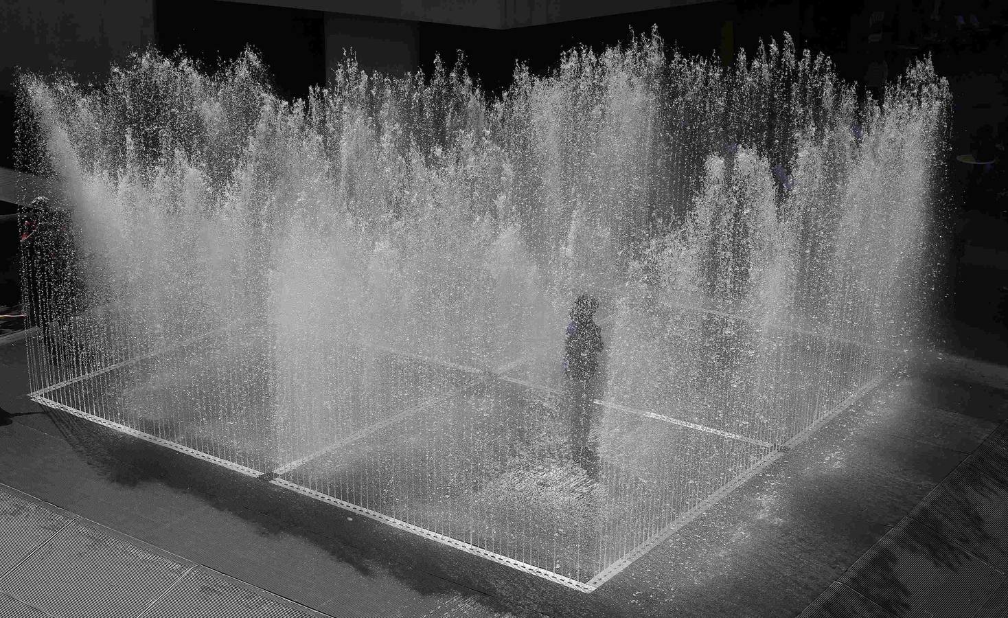 Una mujer se encuentra en el interior de una fuente titulada "Cuartos que aparecen" de Jeppe Hein lo largo del Támesis en el centro de Londres, 16 de julio 2014