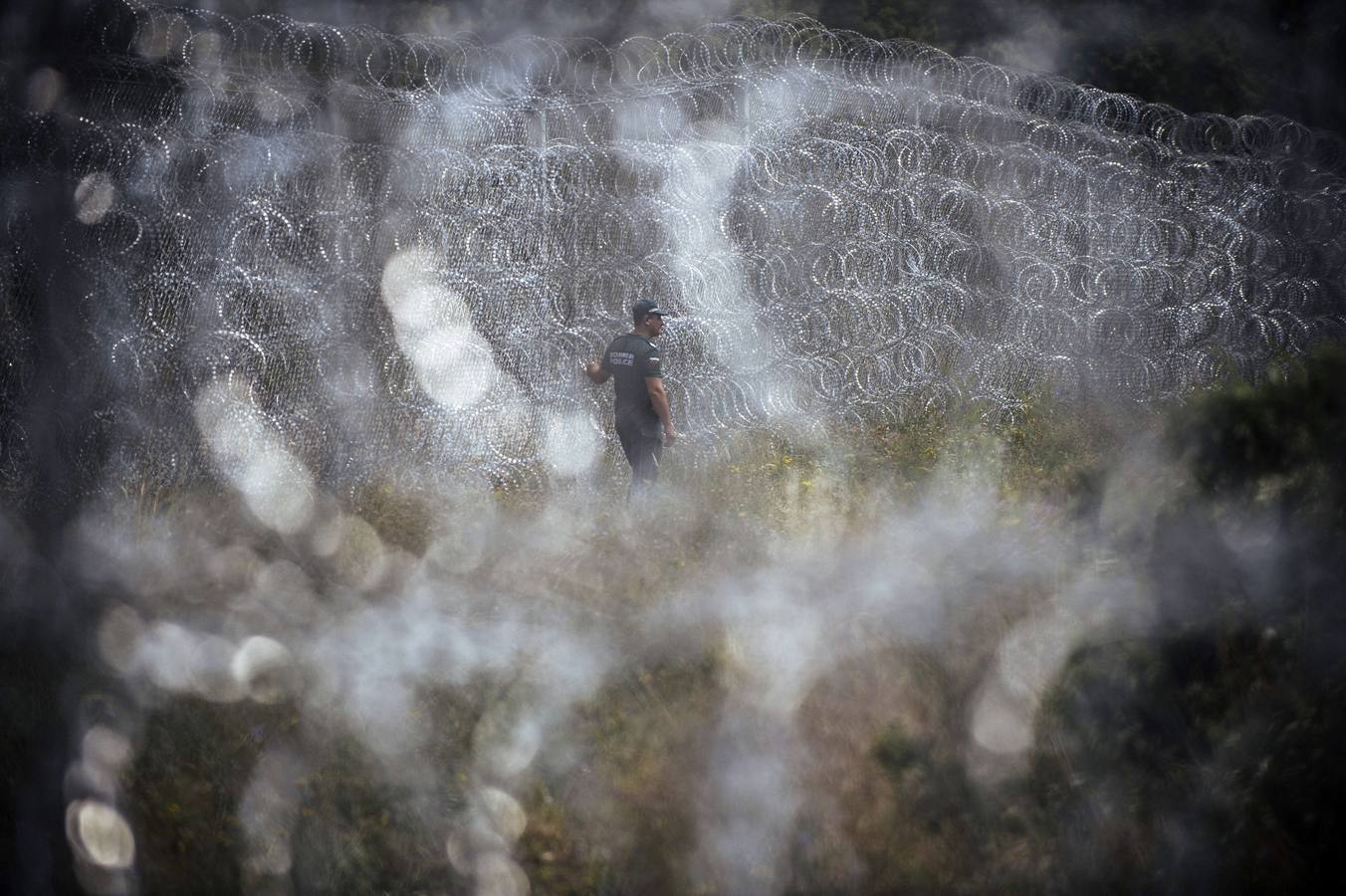 Un policía fronterizo hace guardia junto a un muro de alambre de púas en la frontera búlgara con Turquía, cerca del pueblo de Golyam Dervent.