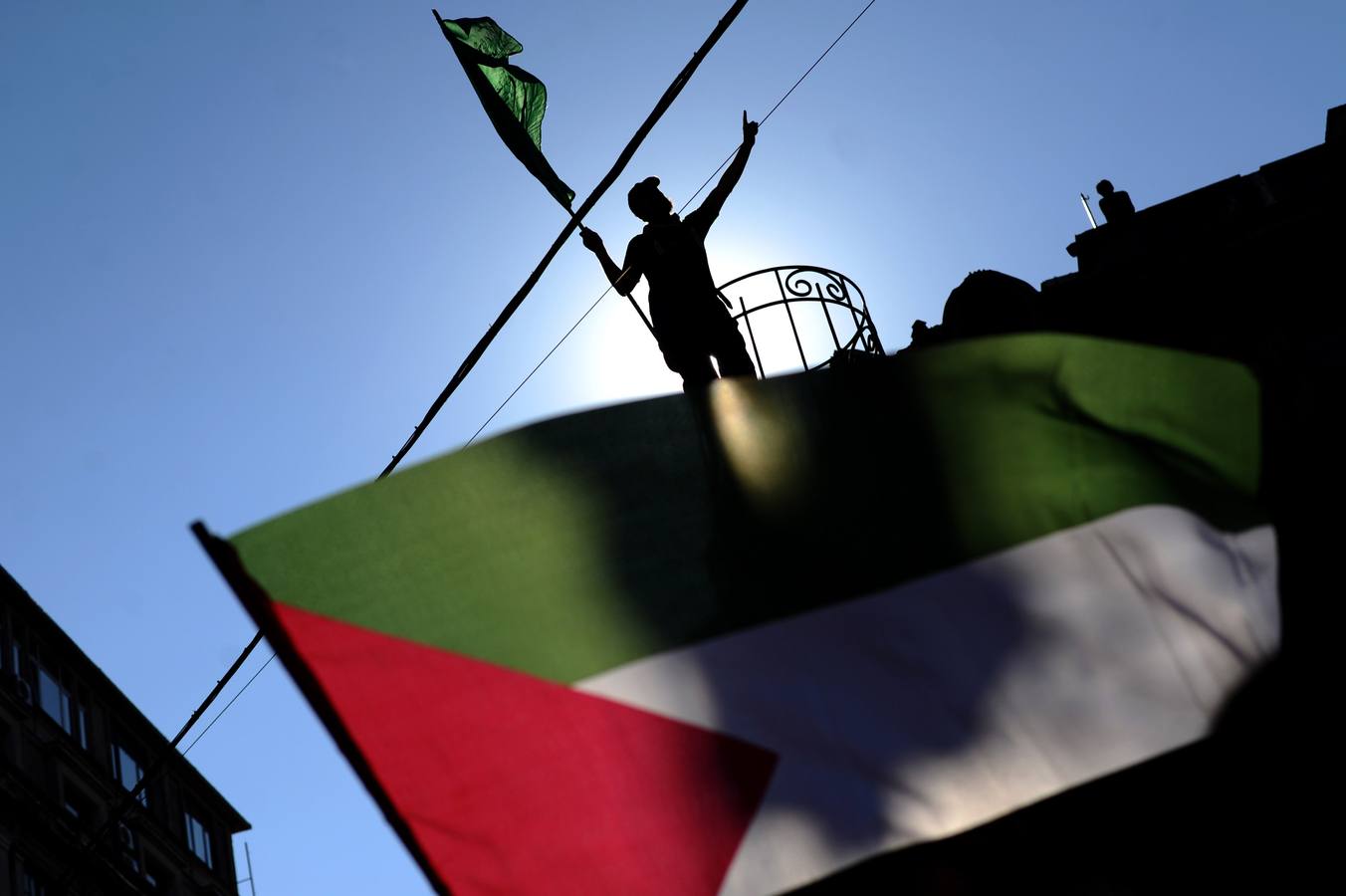 La silueta de un manifestante es visto gesticulando detrás de una bandera palestina durante una manifestación contra el bombardeo israelí de Gaza en la avenida Istiklal en Estambul, Turquía.