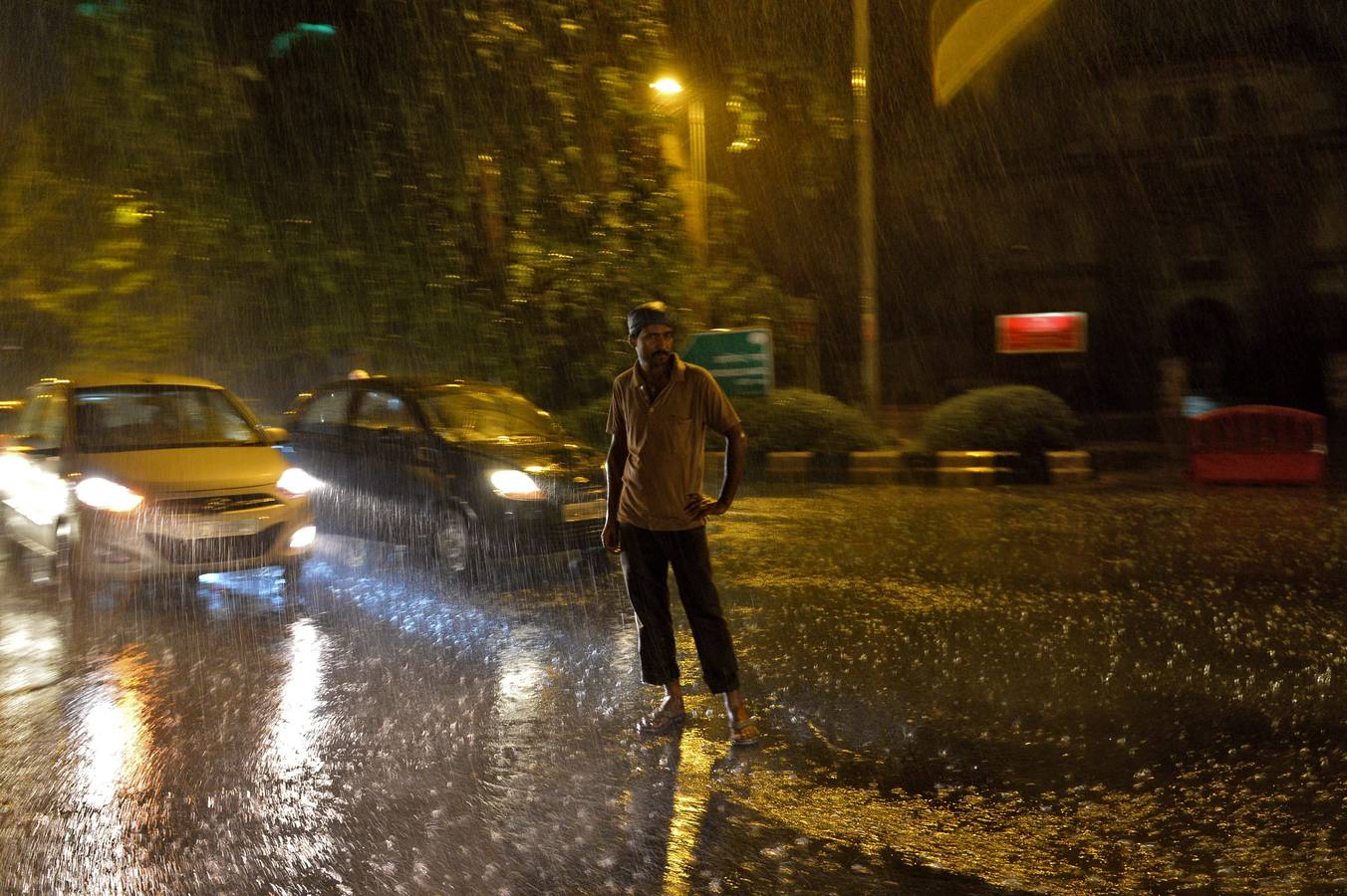 Un peatón indio se encuentra en medio de una calle bajo la lluvia en Nueva Delhi.