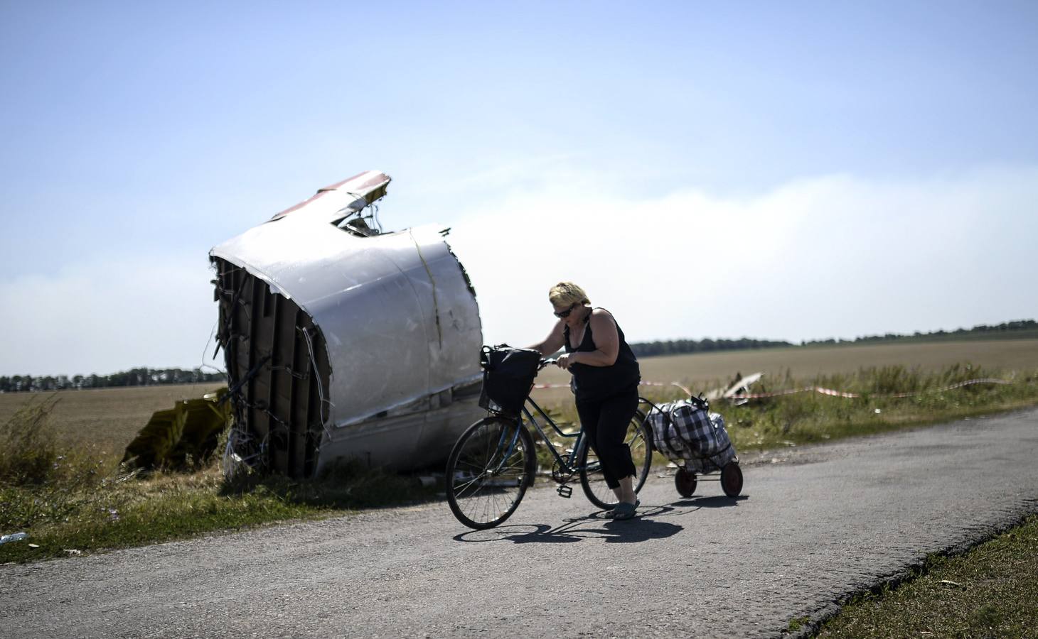 Una mujer camina con su bicicleta cerca del lugar del accidente del Vuelo Malaysia Airlines MH17 en el pueblo de Hrabove (Grabovo).