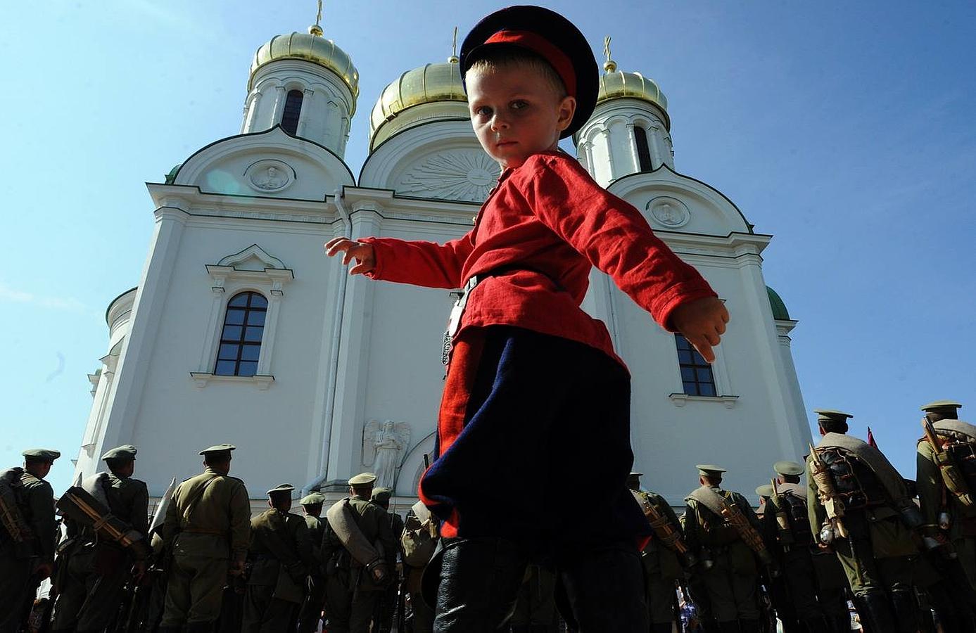 Un niño posa delante de los miembros de un club histórico que participan en una ceremonia para conmemorar el 100 aniversario de la Primera Guerra Mundial en la antigua residencia de los zares rusos en Tsárskoye, San Petersburgo.