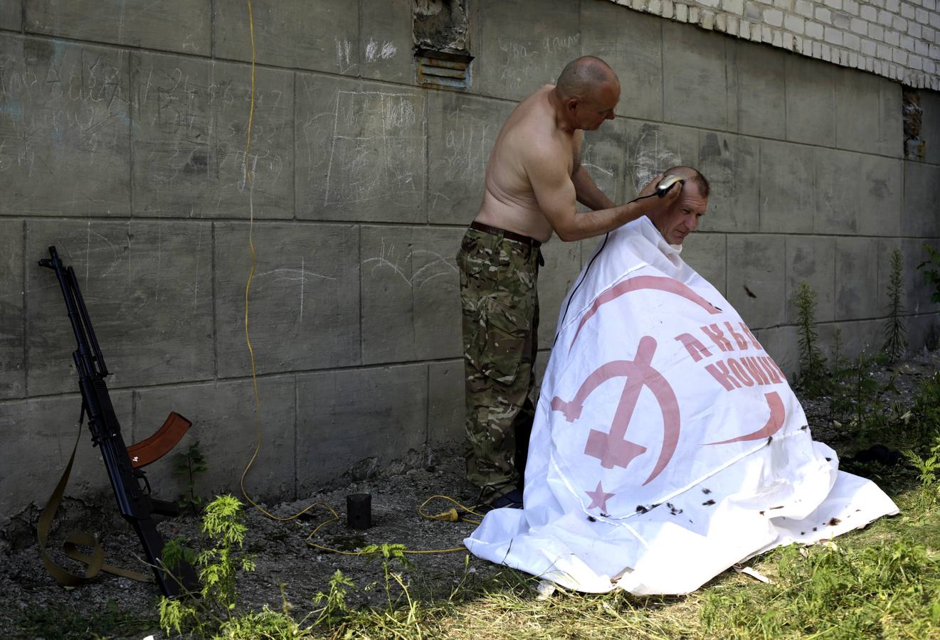 Un militar ucraniano del batallón de voluntarios Donbass cubierto con una bandera del Partido Comunista de Ucrania.