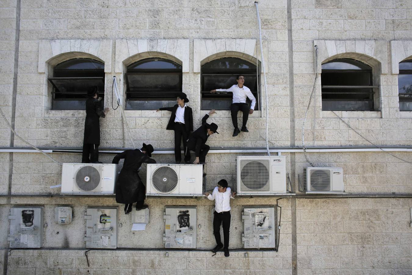 Muchachos judíos ultra-ortodoxos suben por una pared cerca de la escena de un presunto ataque en Jerusalén.