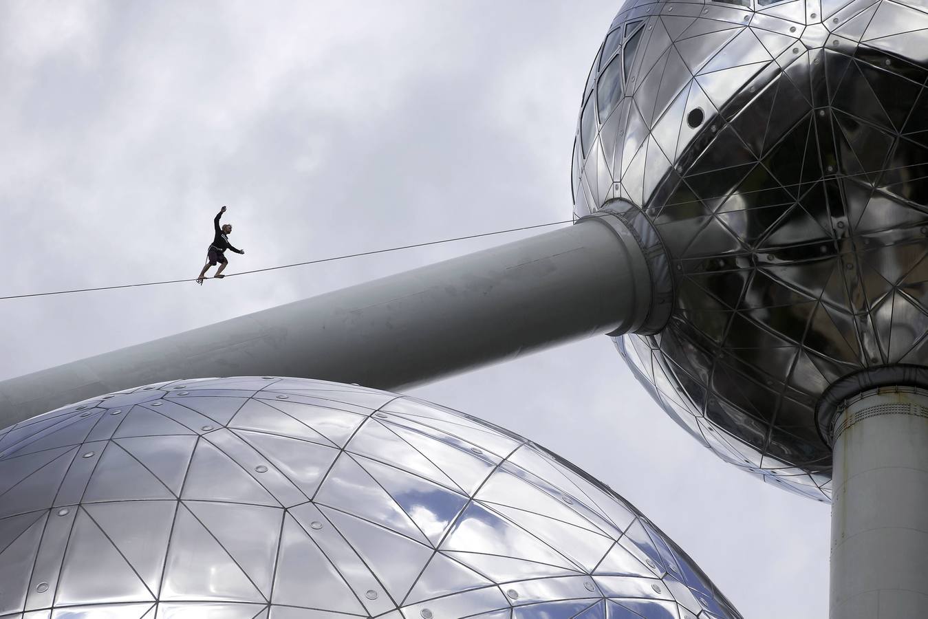 Una persona camina sobre una cuerda floja que conecta las esferas del Atomium, en Bruselas.