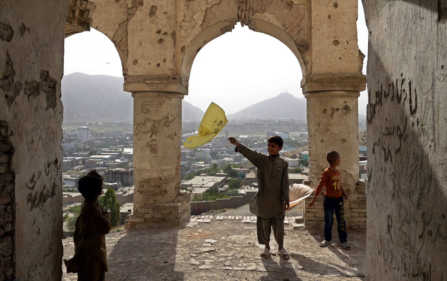 Niños afganos juegan con una cometa en una colina con vistas a Kabul.