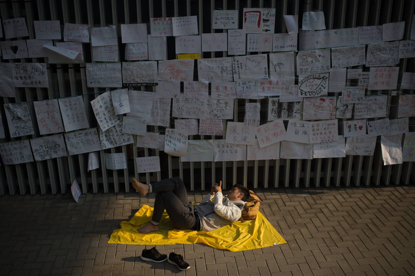 Un manifestante pro-democracia descansa debajo de mensajes de apoyo en el distrito de Almirantazgo de Hong Kong.