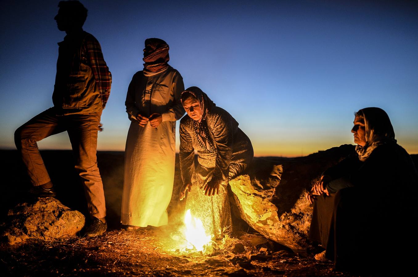 Mujer kurda Ghazal Daban (C), cuyo hijo está luchando en la ciudad siria de Kobane también conocido como Ain al-Arab, mantiene caliente alrededor de una fogata.