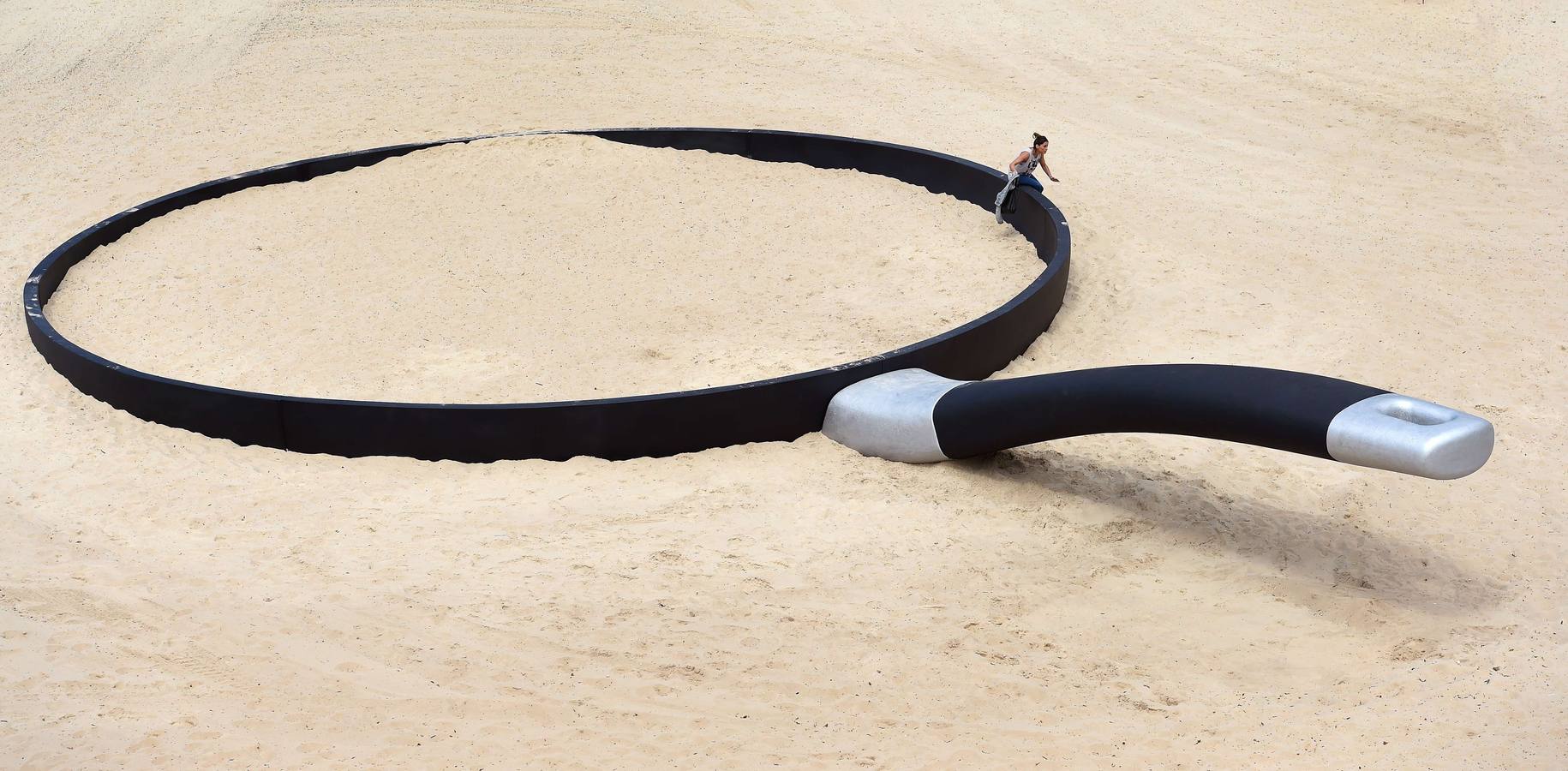 Una mujer sale de una instalación, una sartén gigante del artista Andrew Hankin, titulado "Estamos fryin 'aquí", en Tamarama Beach de Sydney .