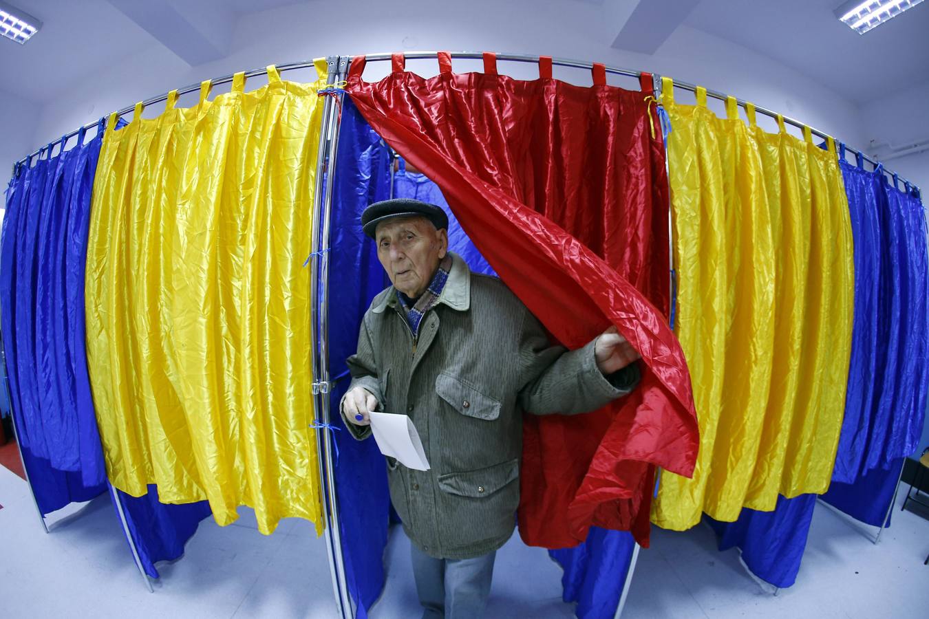 Un hombre sale de una cabina de votación en Bucarest. Imagen tomada con un lente ojo de pez.