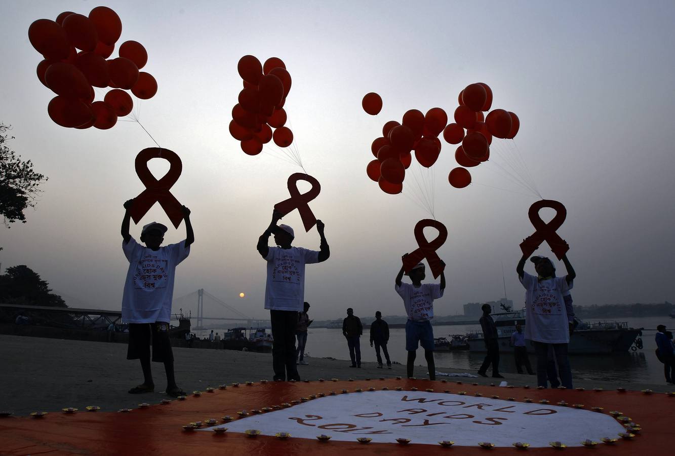 Niños con cintas atadas a globos durante una campaña de sensibilización sobre el VIH / SIDA con motivo del Día Mundial del SIDA en Kolkata.