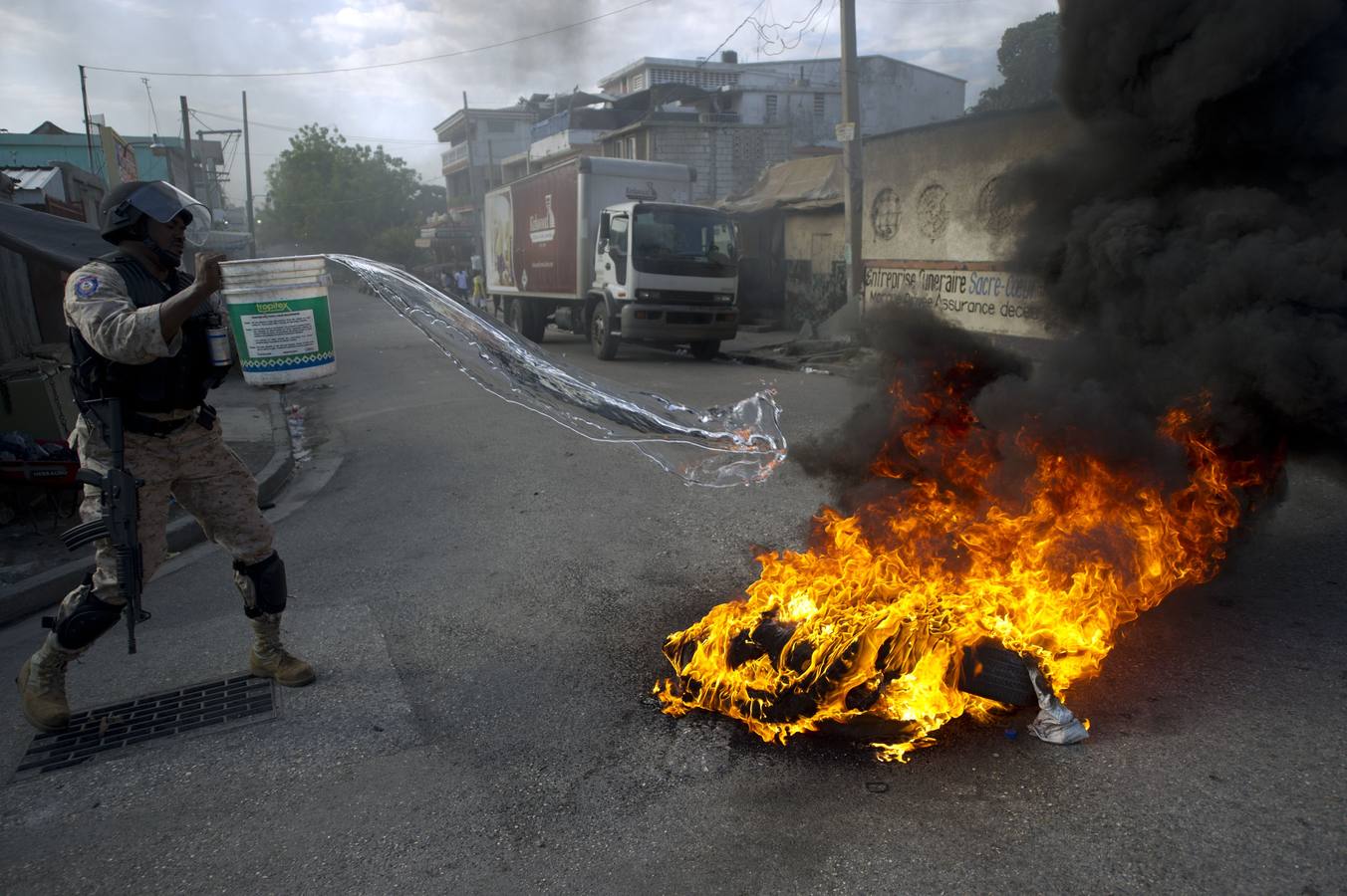 Un policía haitiano intenta extinguir la quema de neumáticos colocados por los manifestantes antigubernamentales.